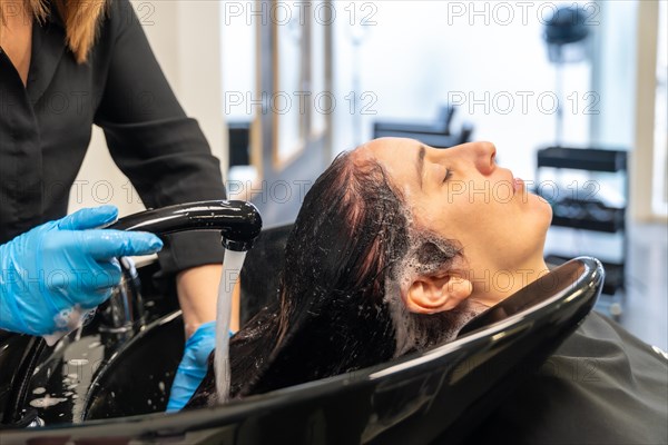 Close-up side view of a caucasian adult relaxed washing her hair in a hair salon