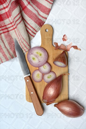 Shallots on wooden board with knife, Allium cepa