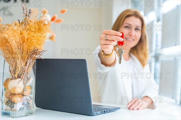 Focus on the hands of a happy female property agent handing over keys in the office