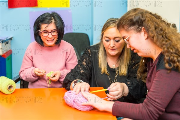 Women with intellectual disabilities and teacher learning how to knit clothes with wool