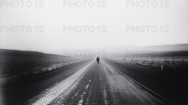 A lone figure walks down a misty road stretching toward the horizon, AI generated