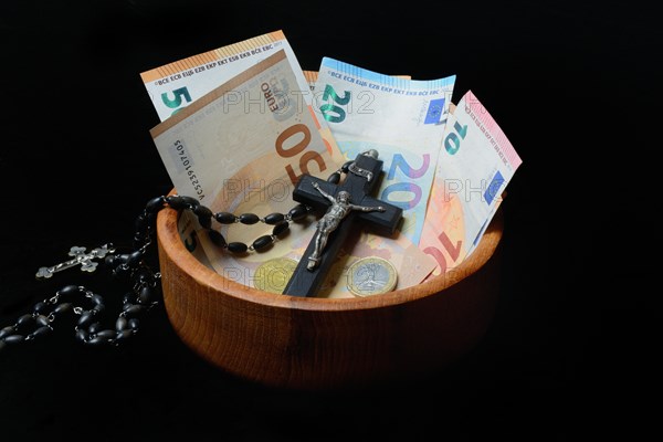 Crucifix and banknotes in a bowl, church and money, church tax