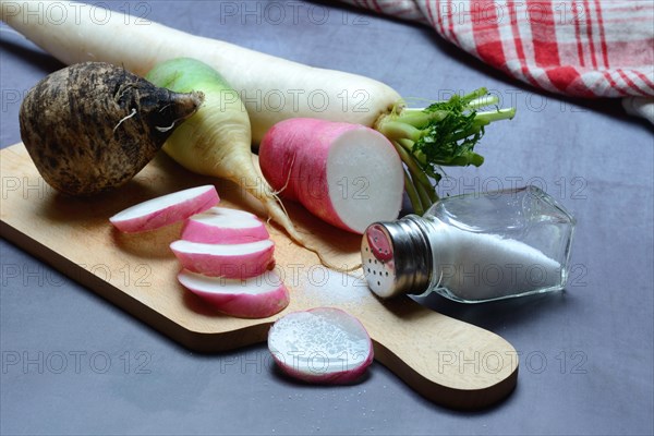 Various radishes on a wooden board, cut up and sliced