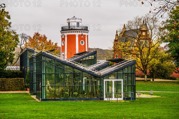 A glass building with a striking red tower in the background, surrounded by an autumnal park, Botanical Garden, Hardt, Elberfeld, Wuppertal, North Rhine-Westphalia