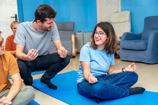 Yoga instructor teaching the lotus position to a disabled woman sitting on a mat in a yoga group class