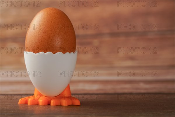 Fresh egg in an egg cup in the shape of a chicken on a wooden table