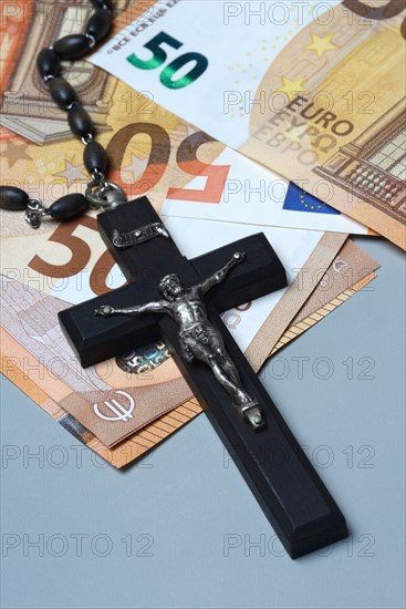 Crucifix and banknotes, church and money, church tax