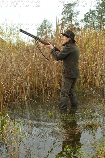 Huntress standing in the water, waiting eagerly for approaching mallards (Anas platyrhynchos) on the occasion of a water hunt for ducks, Allgaeu, Bavaria, Germany, Europe