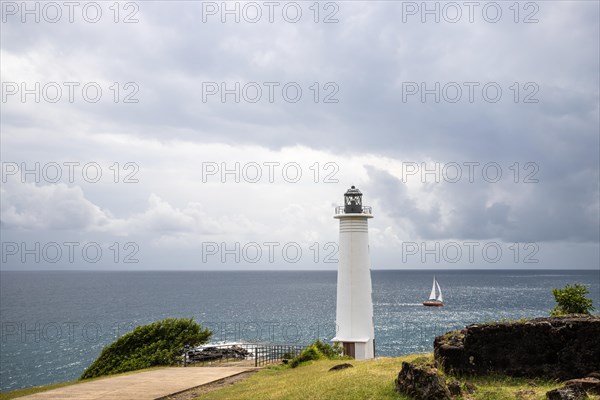 White lighthouse on a steep coast. Dramatic clouds with a view of the sea, pure Caribbean at Le Phare du Vieux-Fort, on Guadeloupe, French Antilles, France, Europe