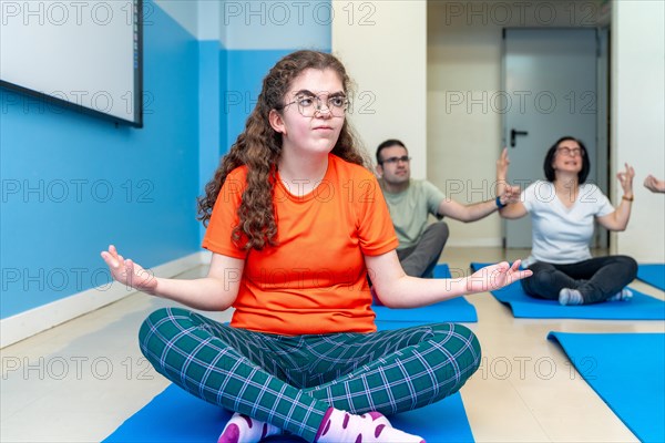 Focus on a disabled woman in lotus position during yoga class next to friends