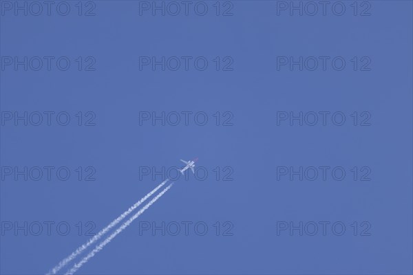 Boeing 737 jet aircraft in flight with a contrail or vapour trail behind in the sky, England, United Kingdom, Europe