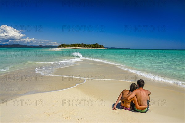 Couple sitting on a beautiful sand tongue, Nosy Iranja near Nosy Be, Madagascar, Africa