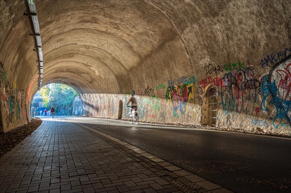 A cyclist rides through a graffiti tunnel with focussed lighting, Nordbahntrasse, Elberfeld, Wuppertal, Bergisches Land, North Rhine-Westphalia