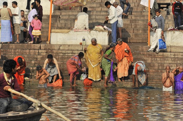 People in traditional dress perform religious rites in river water near stone steps, Varanasi, Uttar Pradesh, India, Asia