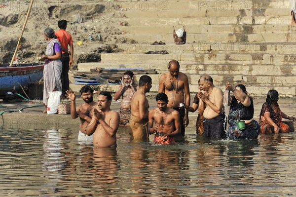A group of people performing traditional rituals in a river, Varanasi, Uttar Pradesh, India, Asia