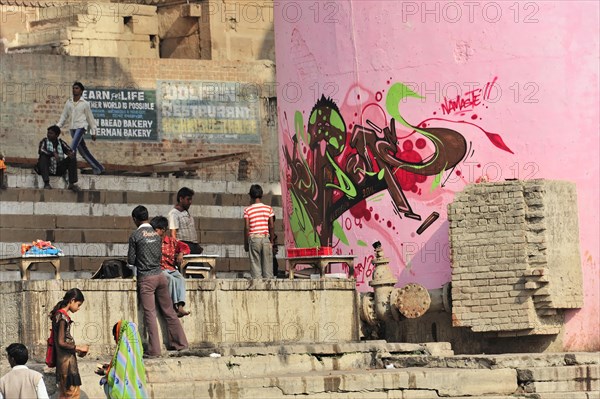 Vibrant graffiti art on a wall next to people in an Indian city, Varanasi, Uttar Pradesh, India, Asia