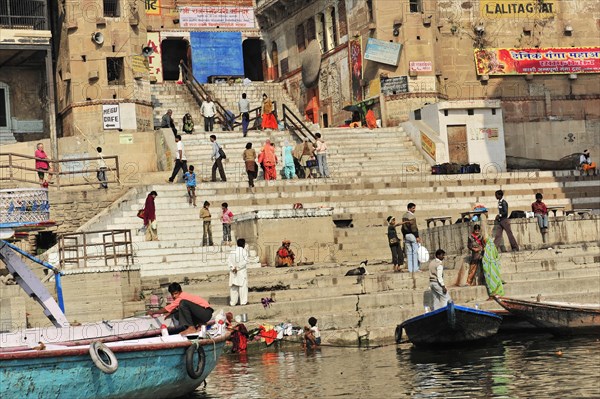 People on the ghats along a river in India with boats in the foreground, Varanasi, Uttar Pradesh, India, Asia