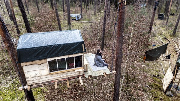 A climate activist sits in a tree house in the Gruenheide forest. The activist group Stop Tesla has built tree houses in the forest to protest against the planned expansion of the Tesla plant, 04.03.2024