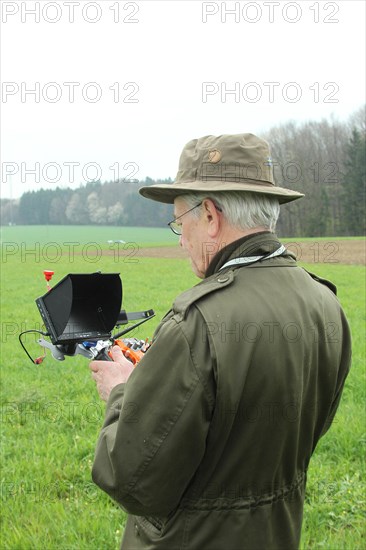 Hunter observes flying drone on the screen of the control unit during a hare (Lepus europaeus) census, Lower Austria, Austria, Europe