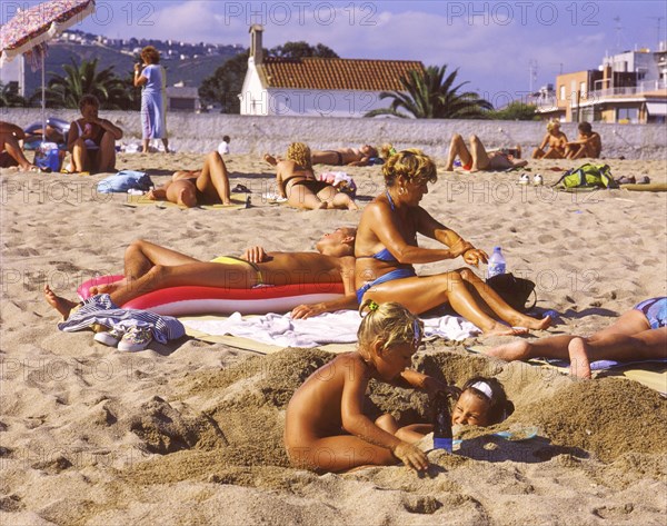 Sunbathers and playing children on the beach in Calella, Costa Brava, Barselona, Catalonia, Spain, Southern Europe. Scanned 6x6 slide, Europe