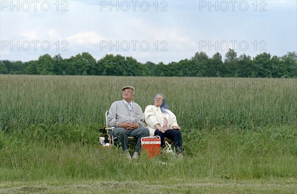 A couple of pensioners sitting on folding chairs at the edge of a field, 10 June 1997