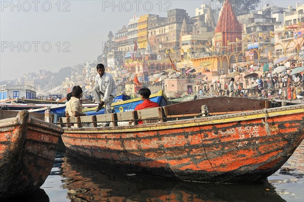 Lively scene on a riverbank with boats and people in front of a city, Varanasi, Uttar Pradesh, India, Asia