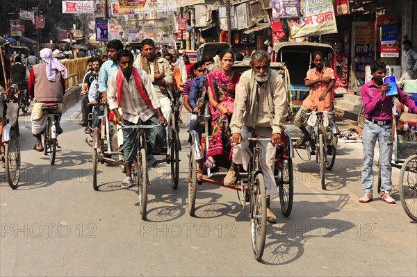 Busy street scene with many cycle rickshaws and passers-by, Varanasi, Uttar Pradesh, India, Asia