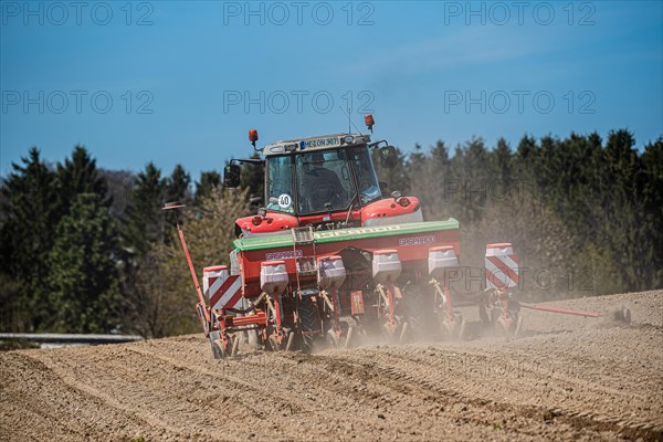 A tractor ploughs a field under a clear sky with swirling dust, Wuelfrath, Mettmann, North Rhine-Westphalia