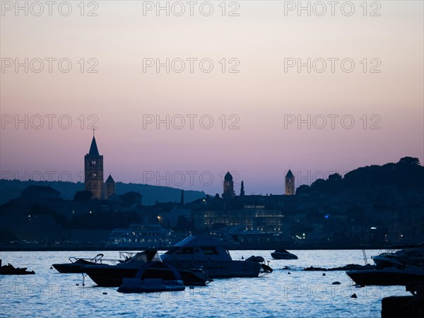 Boats anchoring in a bay, church towers, evening mood after sunset over Rab, town of Rab, island of Rab, Kvarner Gulf Bay, Croatia, Europe