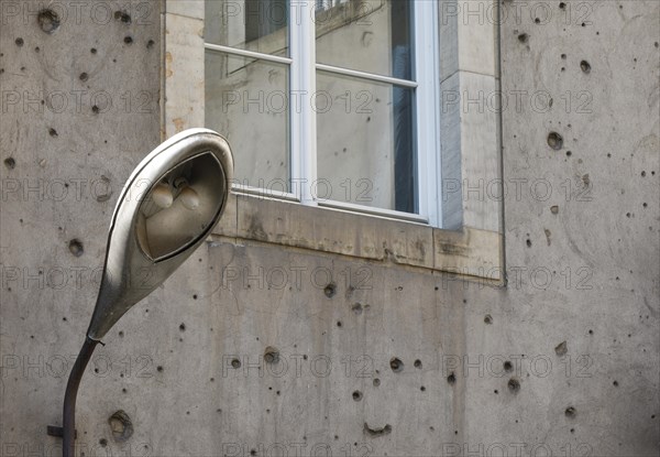 Contemporary history on a building in Berlin Mitte. A lantern from the GDR era on a building that shows clearly visible traces of the Second World War, 08/08/2018