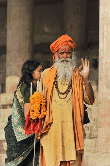Man in orange-coloured traditional dress blessing woman with flower wreath, Varanasi, Uttar Pradesh, India, Asia
