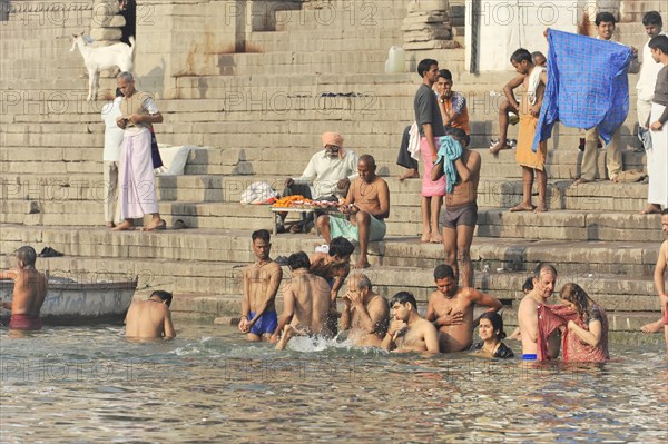 People of different ages bathing in the river and resting on the steps next to it, Varanasi, Uttar Pradesh, India, Asia