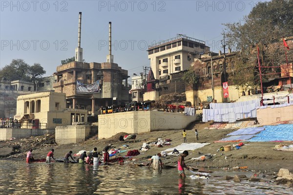 Community washing of clothes on the riverbank with a view of buildings and cultural life, Varanasi, Uttar Pradesh, India, Asia