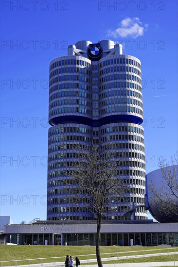 BMW main building, known as the 'four-cylinder', against a clear sky with trees in the foreground, BMW WELT, Munich, Germany, Europe