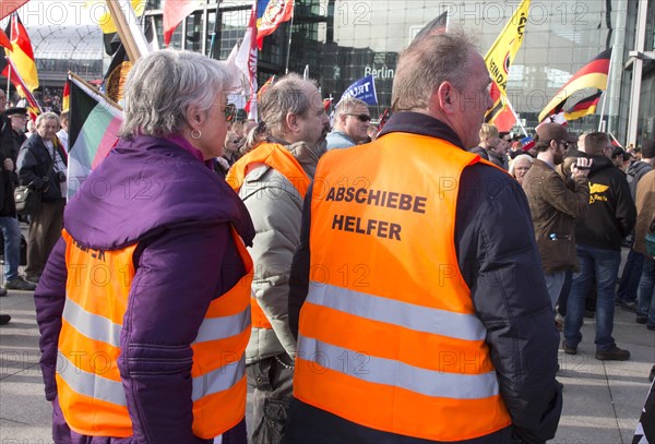 Participants in the Merkel muss weg demonstration wearing waistcoats with the words Abschiebehelfer . Demonstration by right-wing populist and right-wing extremist participants, including supporters of the NPD, Pegida, Reichsbuerger, hooligans, Landsmannschaften and Identitarians, Berlin, 4 March 2017