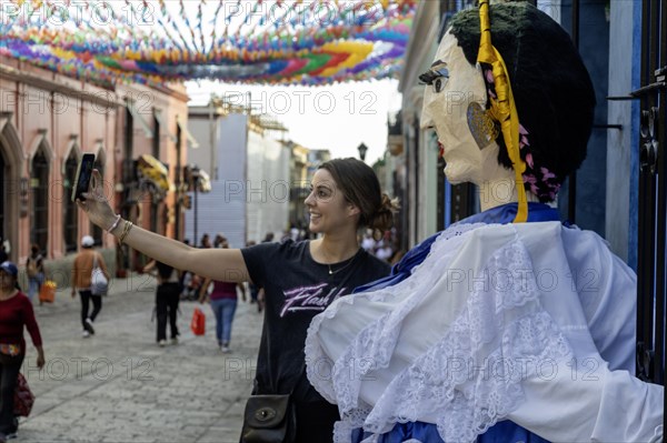 Oaxaca, Mexico, A tourist takes a selfie with a giant papier mache puppet on the Alcala, a pedestrian-only street, Central America