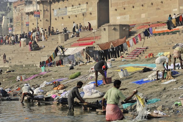 People washing clothes in a river with a cityscape in the background, Varanasi, Uttar Pradesh, India, Asia