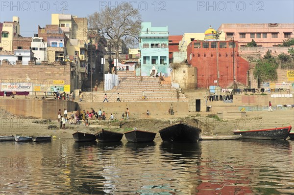 View of a river landscape with banks, boats and city skyline in the background, Varanasi, Uttar Pradesh, India, Asia