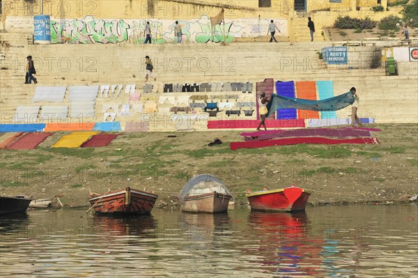 Colourful laundry drying next to a river bank with graffiti in the background, Varanasi, Uttar Pradesh, India, Asia