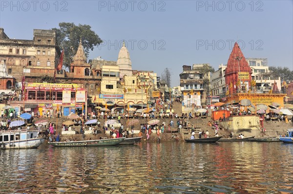Lively activities at the ghats with a view of boats and temples along a river, Varanasi, Uttar Pradesh, India, Asia