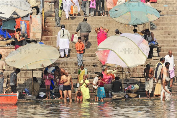 People going about daily activities such as bathing and washing clothes by a river, Varanasi, Uttar Pradesh, India, Asia
