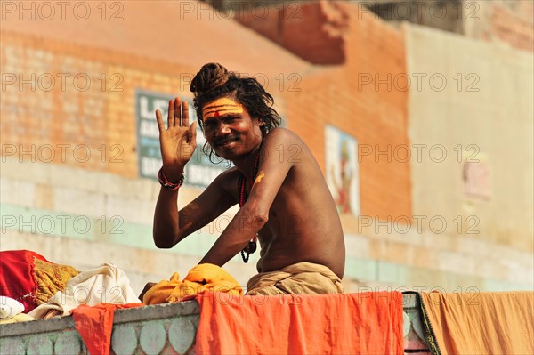 A sadhu at the ghats of Varanasi greets with a painted face and traditional clothing, Varanasi, Uttar Pradesh, India, Asia
