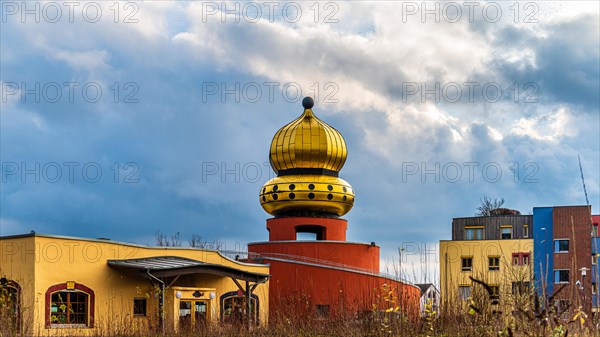 A building with a striking golden dome against a dramatic sky, Hundertwasser Kindergarten, Wuelfrath, Mettmann, North Rhine-Westphalia