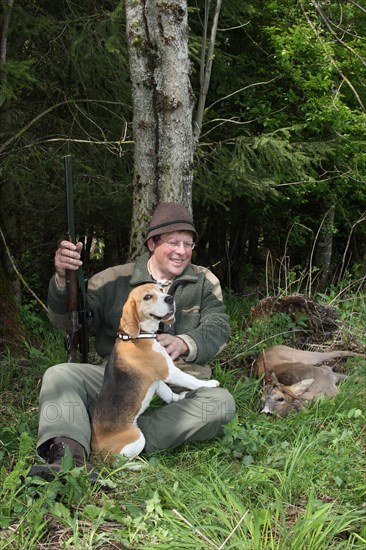 Hunter with hunting dog Beagle enjoying the shot, abnormal european roe deer (Capreolus capreolus) Allgaeu, Bavaria, Germany, Europe