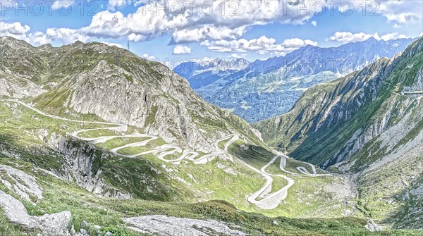 Photo with reduced dynamic saturation HDR of south ramp driveway from steep pass road steeply ascending to mountain pass alpine pass with serpentines tight curves hairpin bends of Tremola southern historical driveway from Airolo to Gotthard pass, in the background mountains in Ticino above cumulus clouds, Canton Uri, Switzerland, Ticino, Italy, Europe
