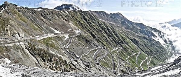 Photo with reduced dynamic saturation HDR of north ramp driveway from steep pass road steeply ascending to mountain pass alpine pass with serpentines tight curves hairpin bends to at Stelvio Pass Stelvio, Stelvio, South Tyrol, Alto Adige, Italy, Europe