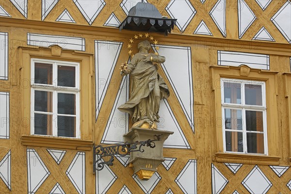 Madonna figure with halo on a yellow half-timbered house, detail, house wall, window, yellow, main street, Ochsenfurt, Lower Franconia, Franconia, Bavaria, Germany, Europe