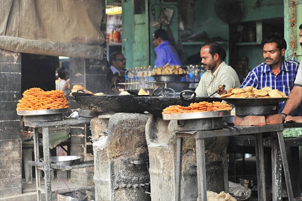 Street vendor preparing deep-fried jalebis and samosas in large pans, Varanasi, Uttar Pradesh, India, Asia
