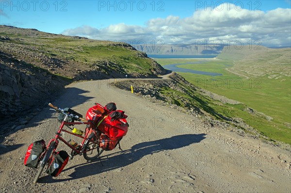Packed bike standing on a gravelled track leading out into a wide valley, Adventure travel, Cycle tourism, Latrabjarg, Iceland, Europe