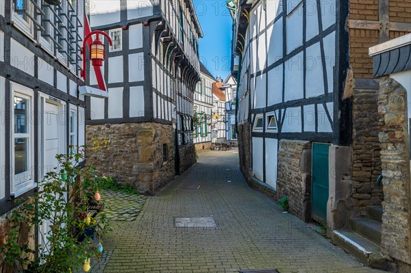 Historic half-timbered houses in an alley with cobblestones and blue sky, Old Town, Hattingen, Ennepe-Ruhr district, Ruhr area, North Rhine-Westphalia